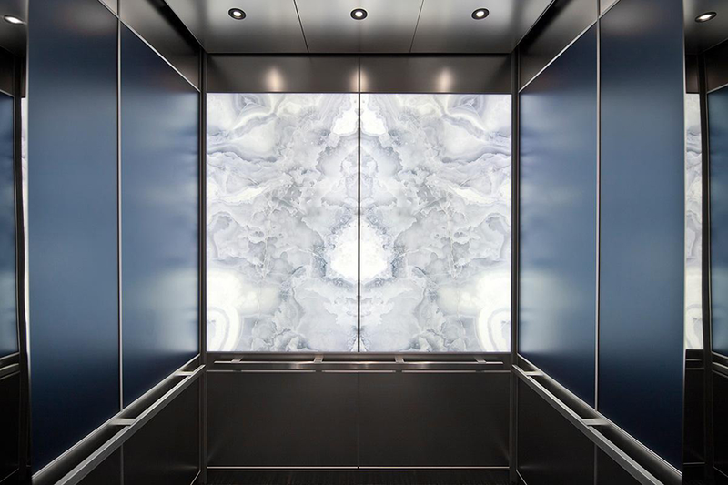 Mẫu cabin thang máy đẹp ốp đá nhân tạo có bề mặt sáng cùng đường vân độc đáo, màu sắc mới lạ tạo điểm nhấn cho không gian thang máy